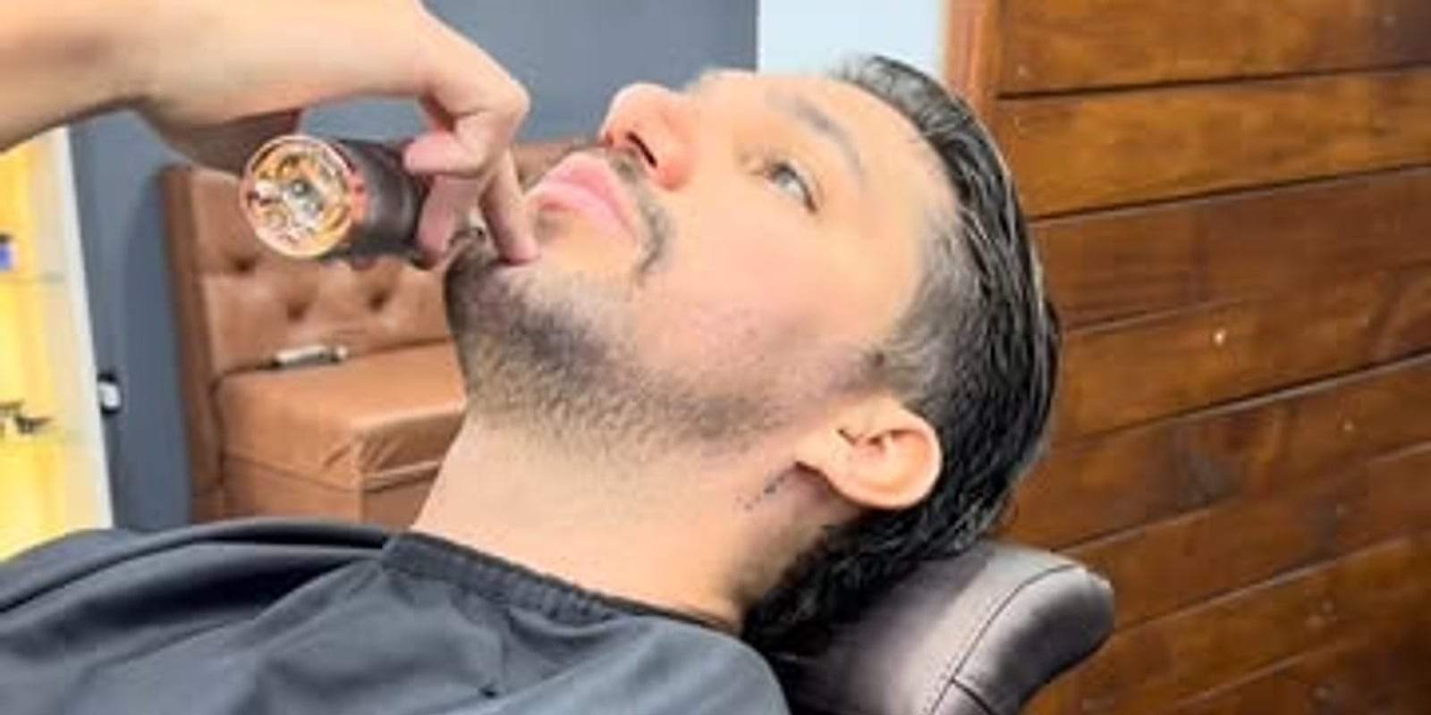 Cliente reclinado na cadeira durante o acabamento da barba